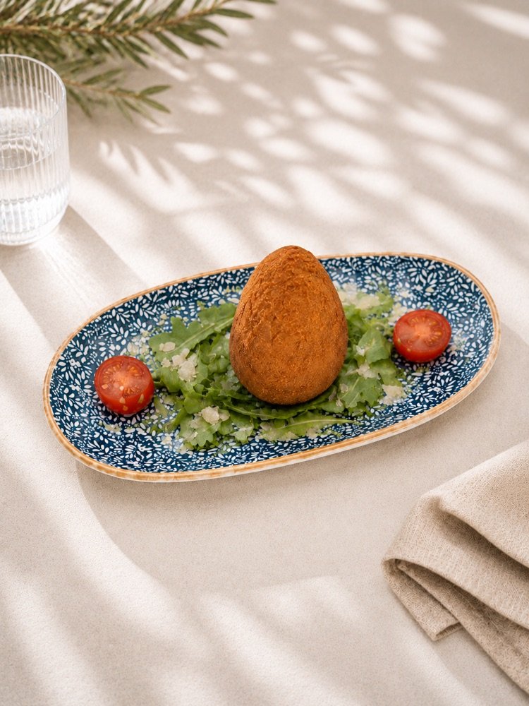 Frittierter Arancino mit knuspriger Panade auf Rucola mit Parmesan und Cherrytomaten